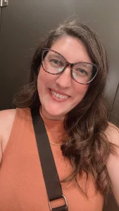 Portrait of Jayna Clouse smiling and wearing glasses, featured in her first time surrogate story about beginning the surrogacy journey.