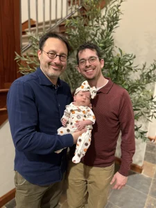 Alan and Brett, Kansas City intended parents, holding their newborn daughter Dorothea Rose shortly after her birth through surrogacy with Pathways to Parenthood.